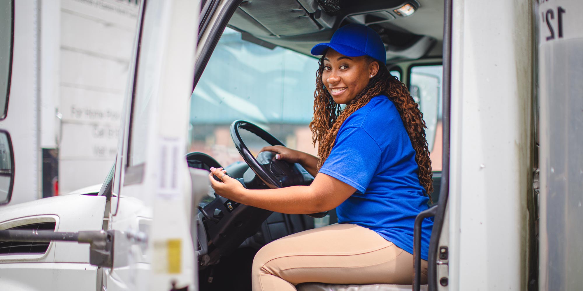 a smiling woman driving a box truck