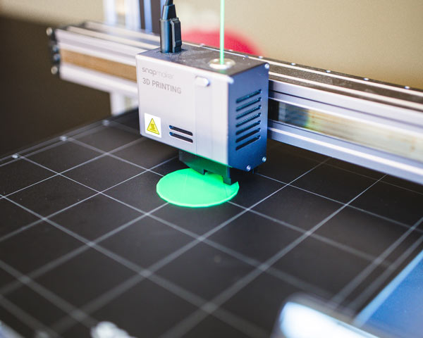 closeup of a 3D printer printing a green medallion